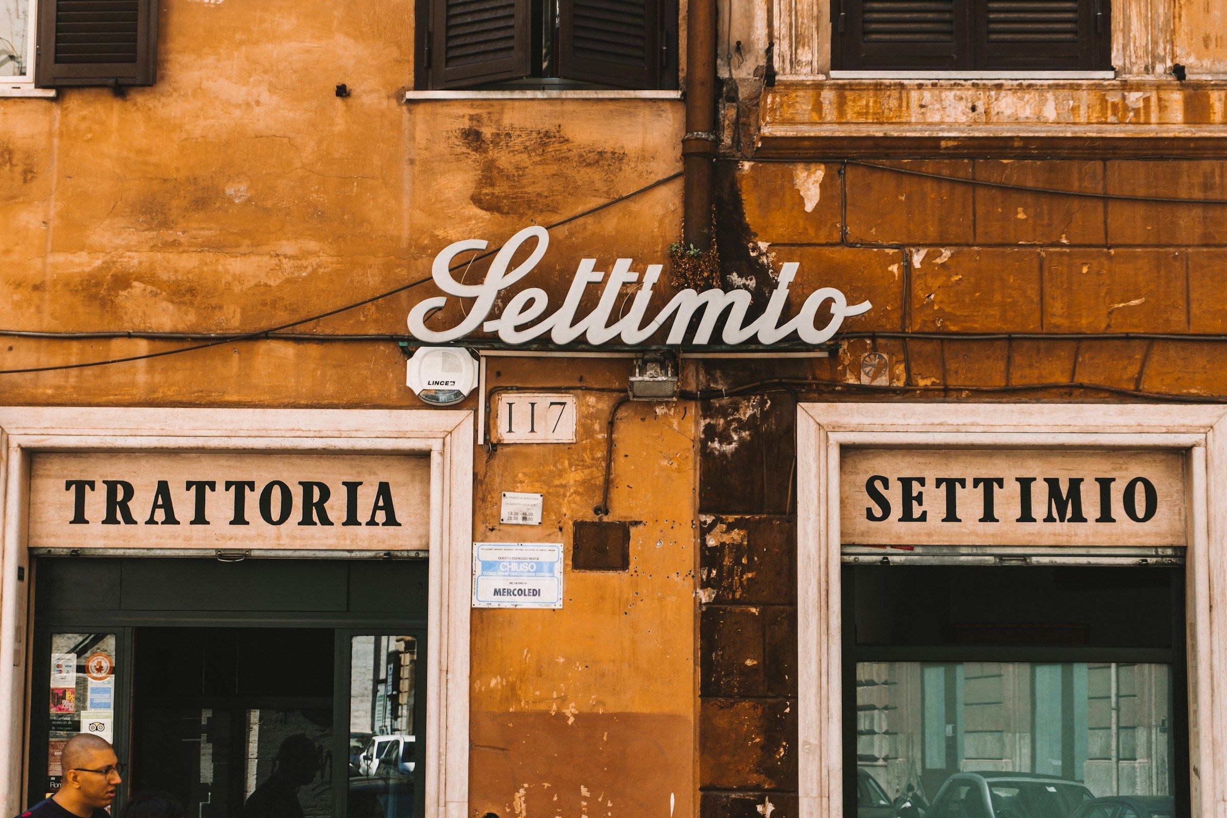 The sign of a traditional trattoria on an ochre wall